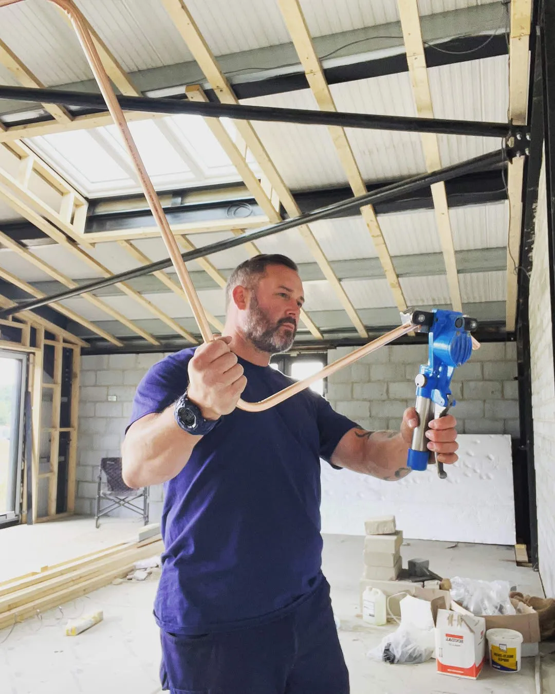 Engineer bending copper pipework during a refrigeration installation in a steel-framed commercial building