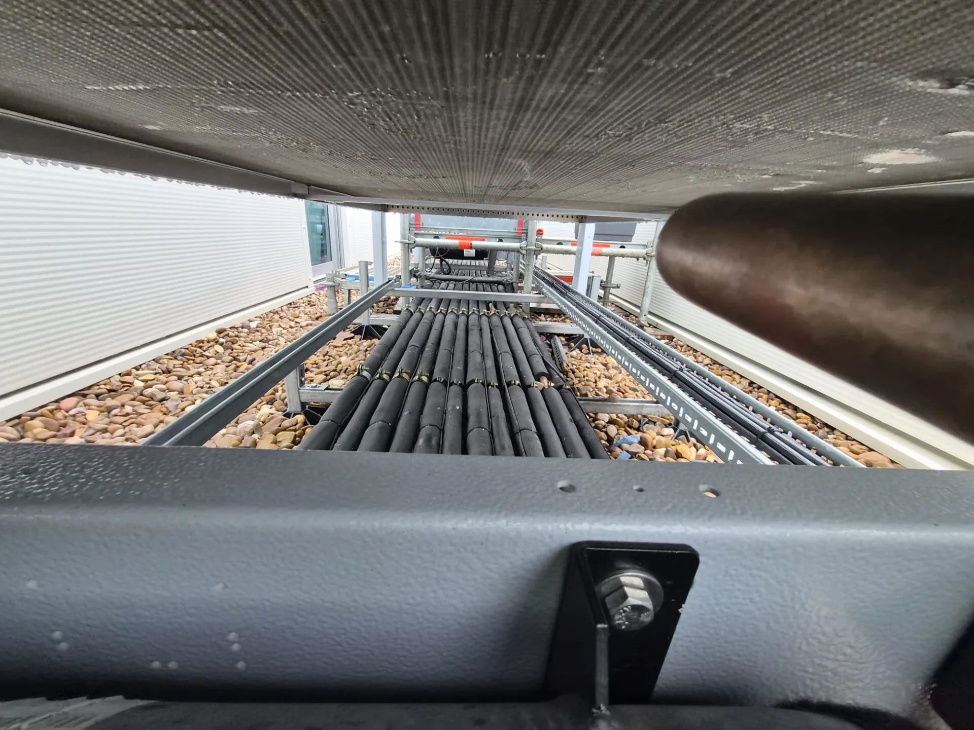 Pipework and supports installed beneath a commercial outdoor refrigeration unit